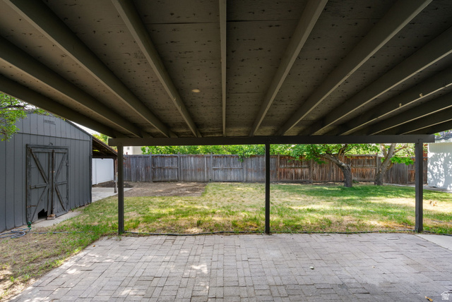 432 Calnette Drive Sandy, UT 84070 - Photo 41 of 48 Covered patio with paver flooring, offering a direct view of the backyard's manicured lawn and mature trees