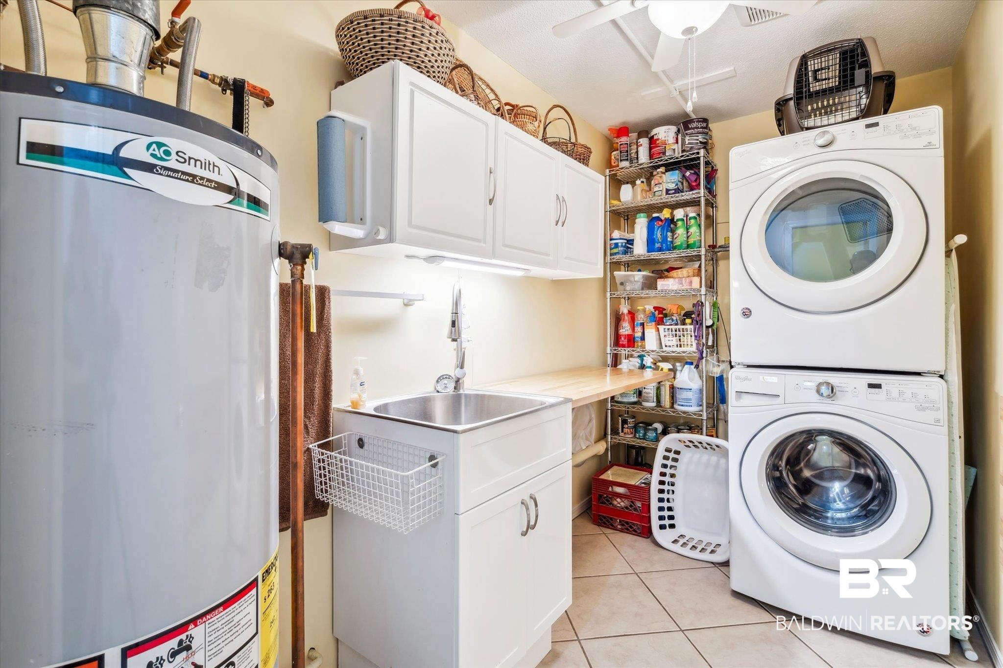 8710 Three Notch Road Mobile, AL 36619 - Photo 21 of 30 Laundry area featuring light tile patterned floors, cabinets, ceiling fan, water heater, and stacked washing maching and dryer