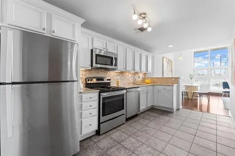a kitchen with cabinets stainless steel appliances and a window