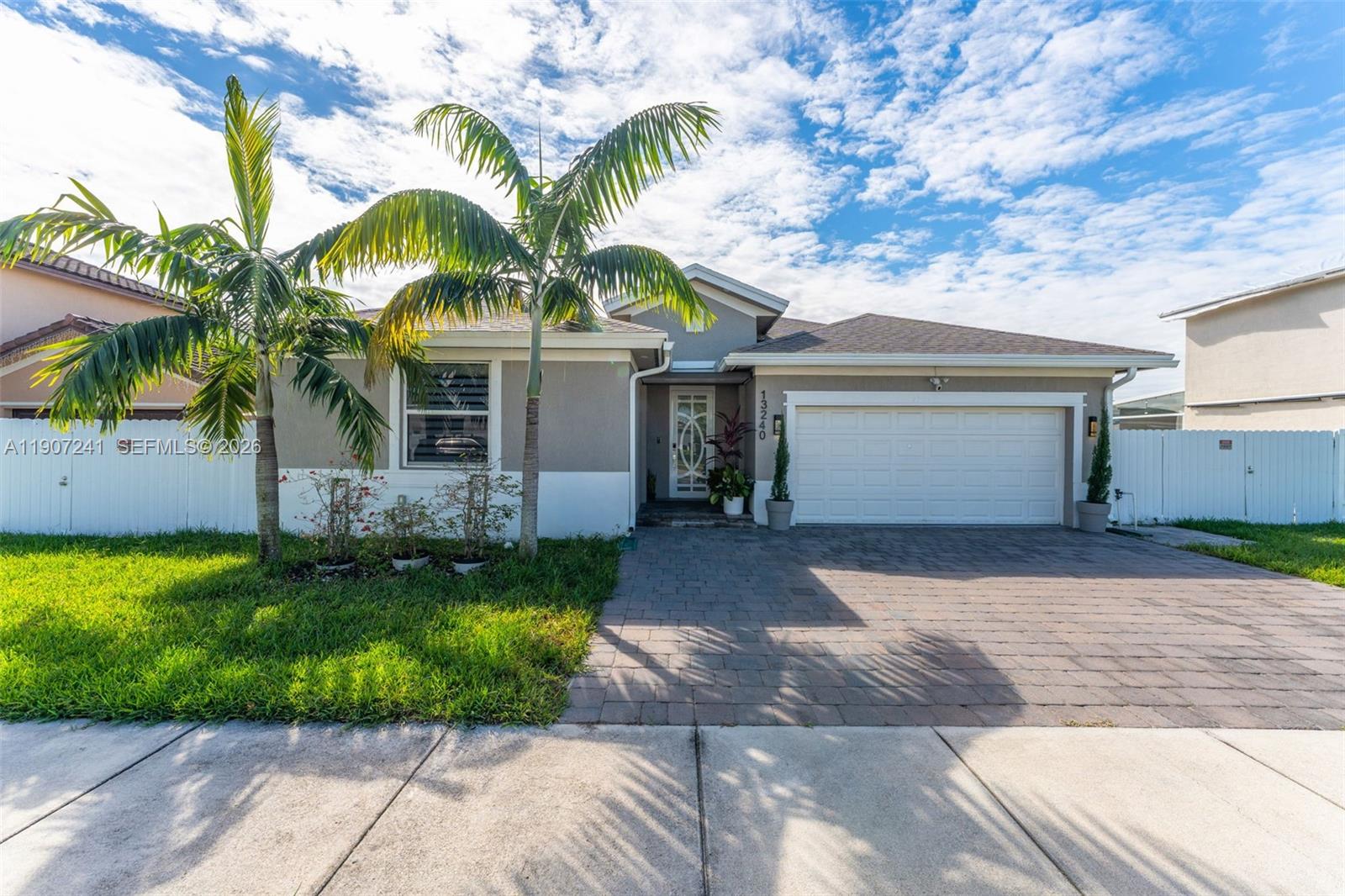 13240 Southwest 274th Street Homestead, FL 33032 - Photo 1 of 54 a front view of a house with a garden and palm trees