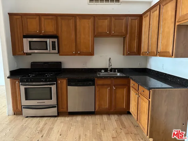 a kitchen with stainless steel appliances a stove a microwave and a sink