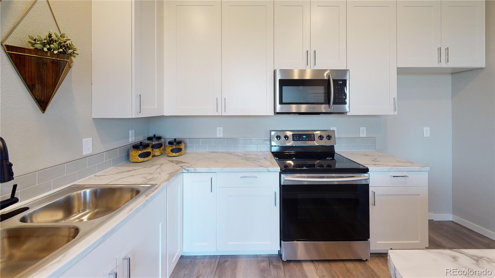 1353 Reynolds Street, Unit 9B Fort Lupton, CO 80621 - Photo 6 of 14 a kitchen with granite countertop a sink stove and microwave