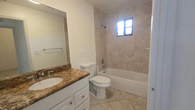 a bathroom with a granite countertop toilet a sink and a mirror