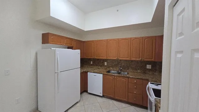 a kitchen with a refrigerator a stove a sink and cabinets
