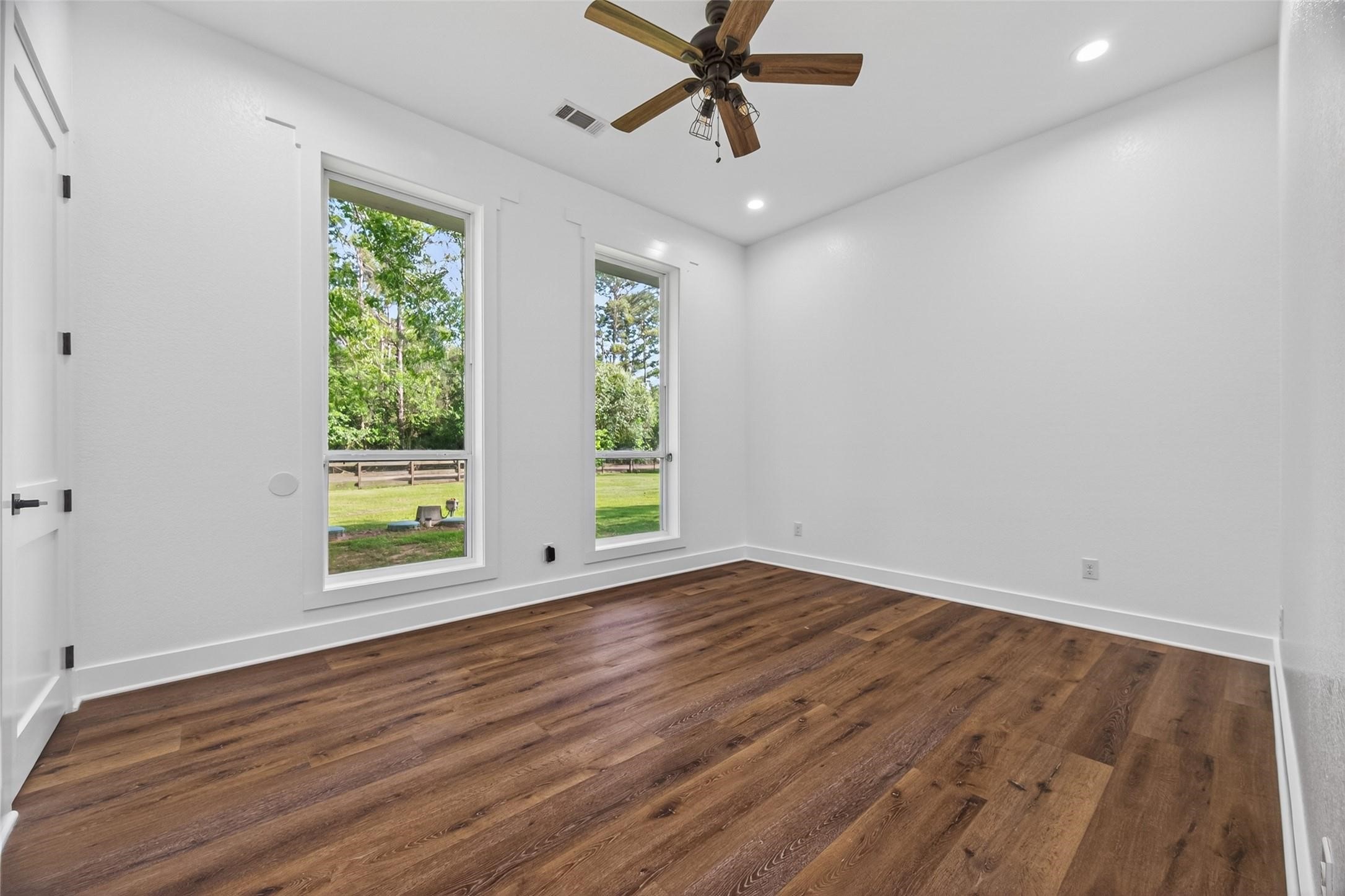 12625 Padon Road Needville, TX 77461 - Photo 16 of 50 Serene bedroom retreat featuring oversized windows, warm wood flooring, and peaceful outdoor views, creating a bright and calming atmosphere.