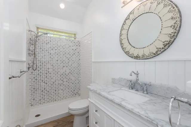 a bathroom with a granite countertop sink a toilet and shower