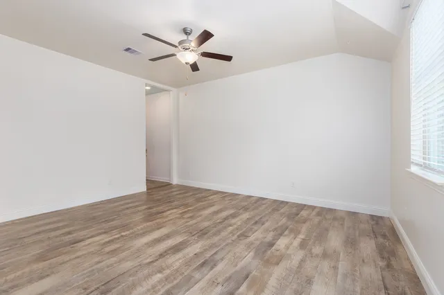 an empty room with wooden floor and ceiling fan