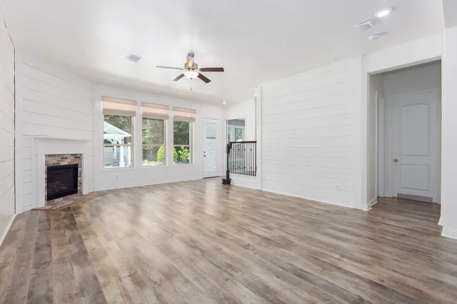 a view of an empty room with window and wooden floor