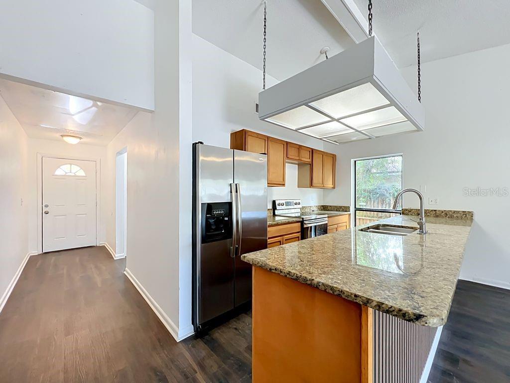 5214 2nd Street Orlando, FL 32810 - Photo 16 of 50 a kitchen with stainless steel appliances granite countertop a sink a refrigerator and wooden floor