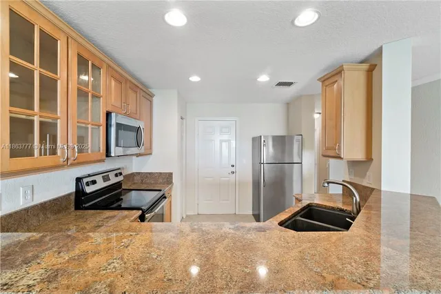 a kitchen with granite countertop a refrigerator and a sink