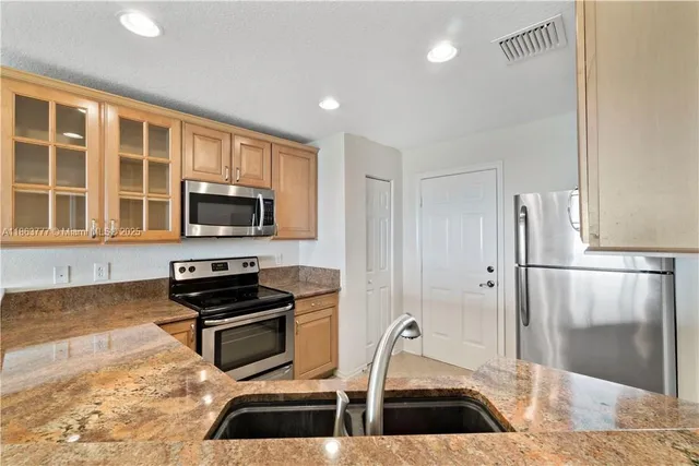 a kitchen with granite countertop a refrigerator and a sink