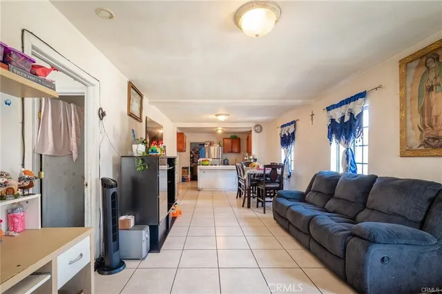 a living room with furniture a dining table and a refrigerator