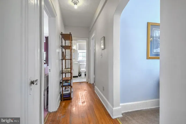 a view of a hallway with wooden floor and a living room