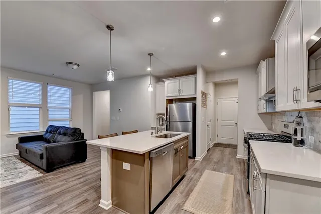 a kitchen with kitchen island granite countertop a sink a counter top space appliances and cabinets