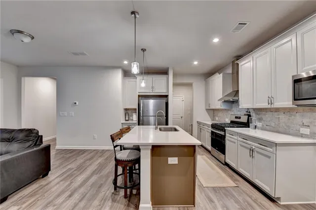 a kitchen with kitchen island a stove a refrigerator a sink and white cabinets with wooden floor