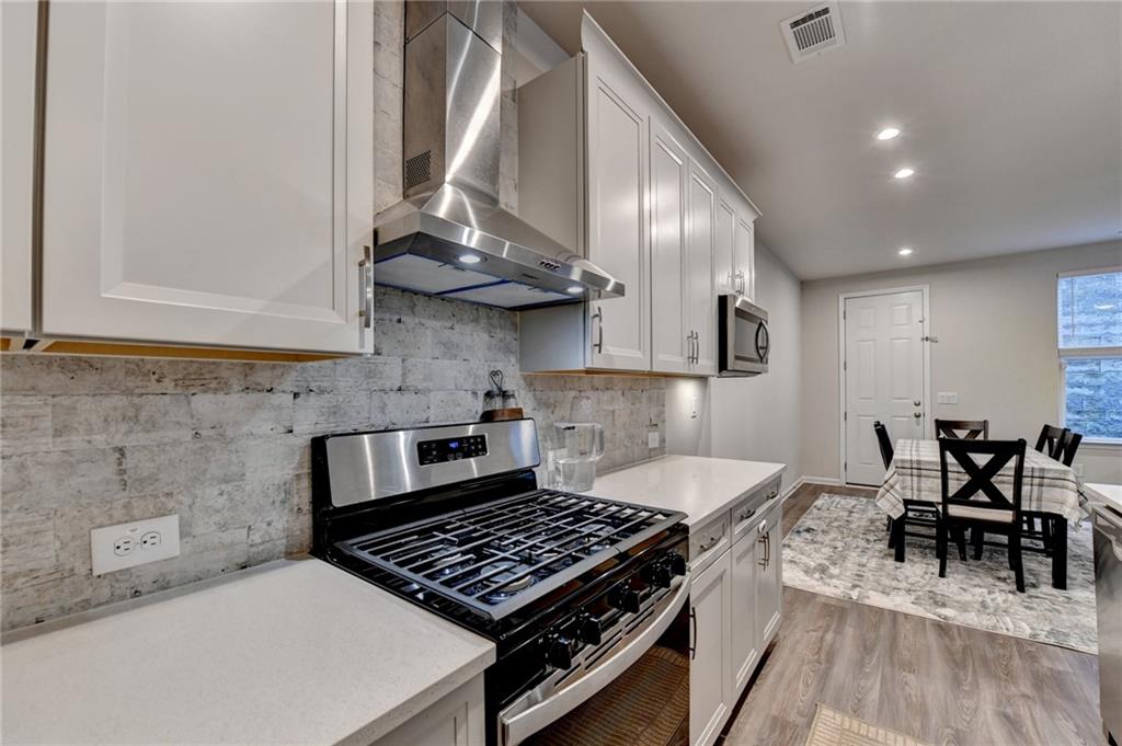 682 Smokey Quartz Way Kennesaw, GA 30144 - Photo 20 of 49 a kitchen with stainless steel appliances granite countertop a stove a sink and a dining table with wooden floor