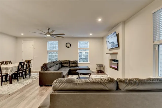 a large living room with stainless steel appliances granite countertop a couch a stove a sink a dining table and chairs with wooden floor