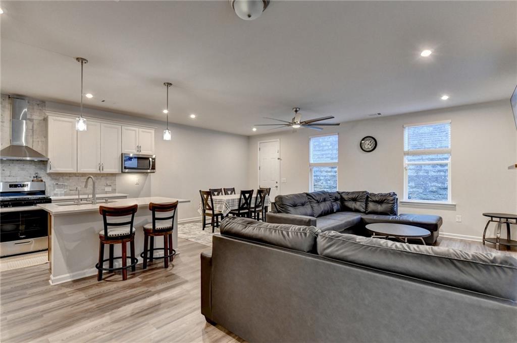 682 Smokey Quartz Way Kennesaw, GA 30144 - Photo 7 of 49 a large living room with stainless steel appliances granite countertop a couch a stove a sink a dining table and chairs with wooden floor
