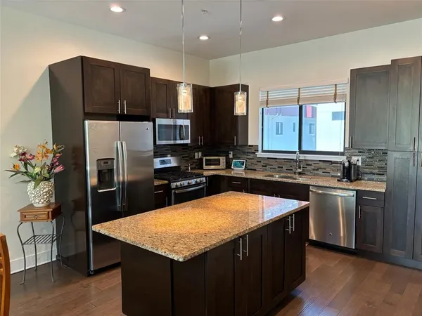 a kitchen with stainless steel appliances granite countertop a sink refrigerator and microwave