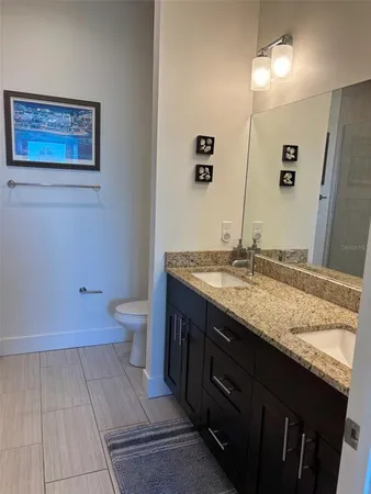 a bathroom with a granite countertop sink a toilet and a mirror
