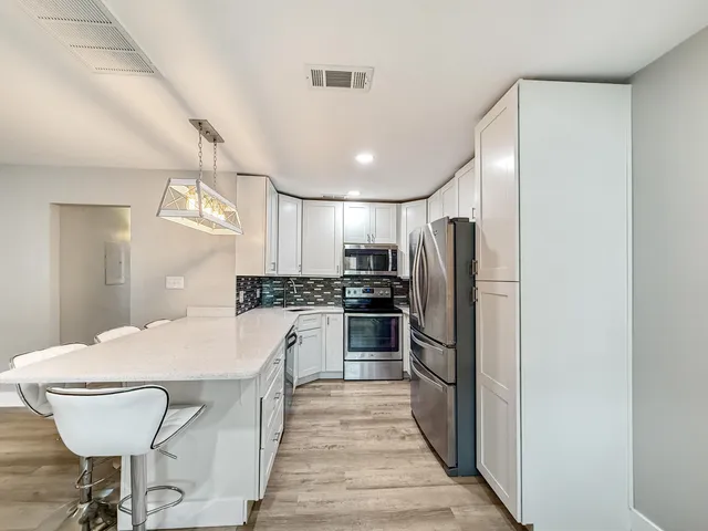 a kitchen with refrigerator and chairs