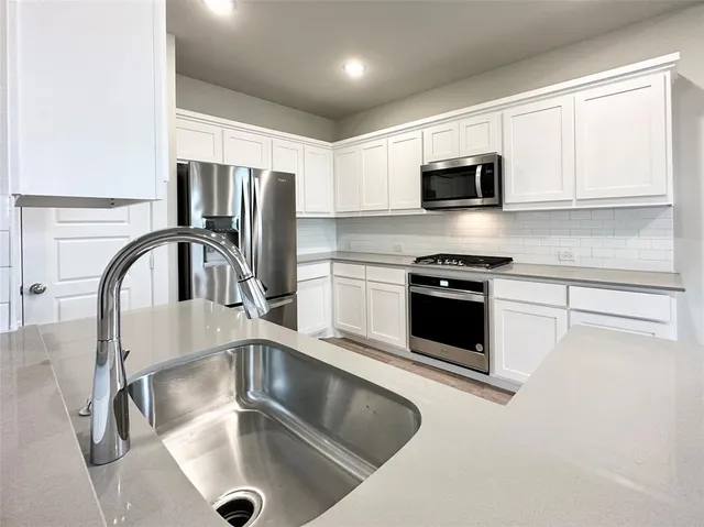 a kitchen with stainless steel appliances granite countertop a sink a microwave and cabinets