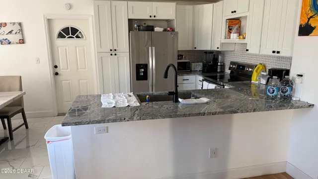 a kitchen with stainless steel appliances granite countertop a sink a refrigerator and a granite counter tops