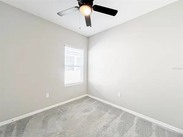 an empty room with a window and a fan