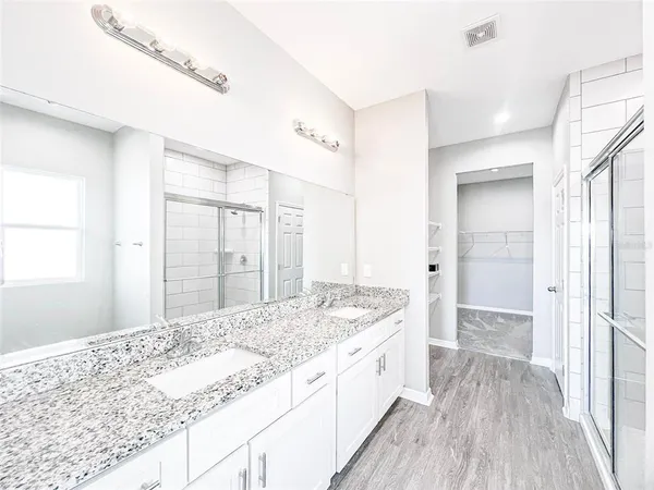 a bathroom with a granite countertop sink a toilet a large mirror and shower