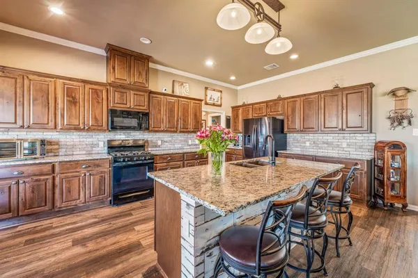 a kitchen with kitchen island granite countertop a stove cabinets and wooden floor