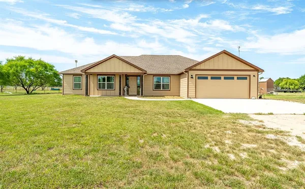 a front view of a house with a yard and trees