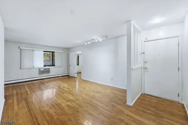 a view of an empty room with window and wooden floor