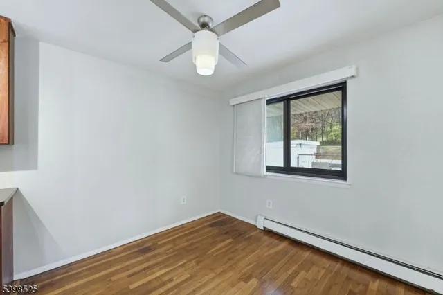 an empty room with wooden floor fan and windows