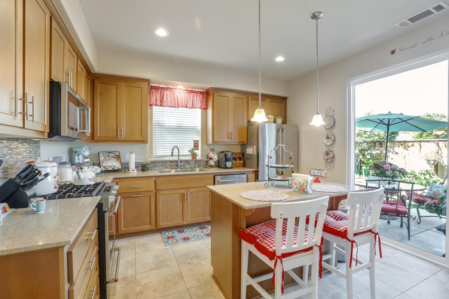 260 Springtime Circle Hollister, CA 95023 - Photo 10 of 46 a kitchen with a dining table chairs sink and white cabinets