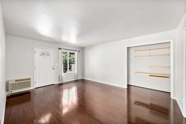 an empty room with wooden floor closet and windows