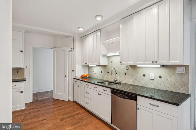 a kitchen with stainless steel appliances granite countertop a sink and cabinets with wooden floor