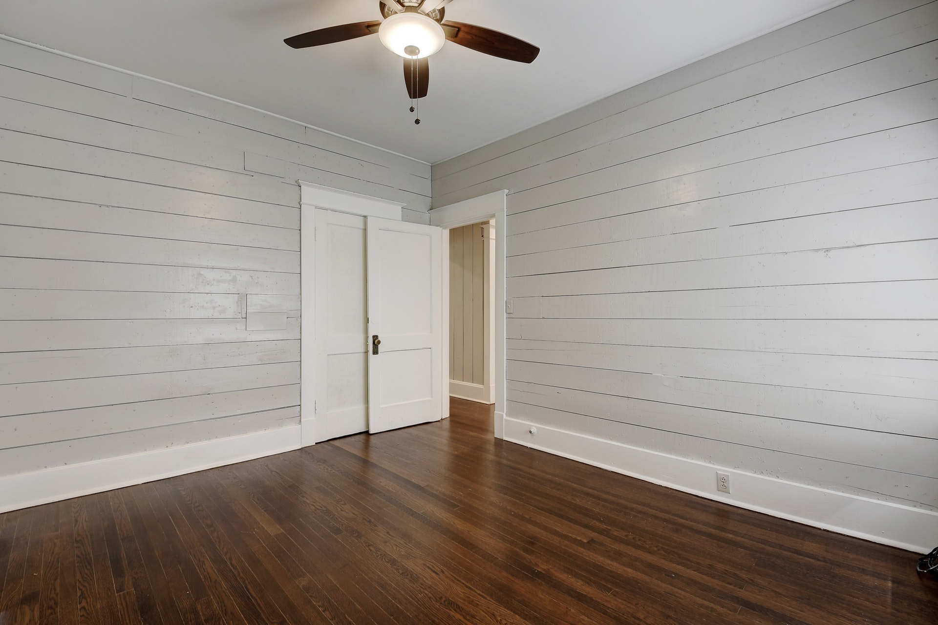 903 Shoal Cliff Court Austin, TX 78705 - Photo 16 of 31 an empty room with wooden floor chandelier fan and windows
