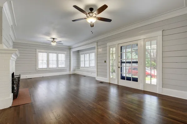 a view of an empty room with wooden floor and a window