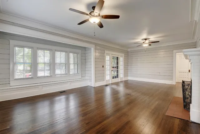 a view of empty room with wooden floor and fan