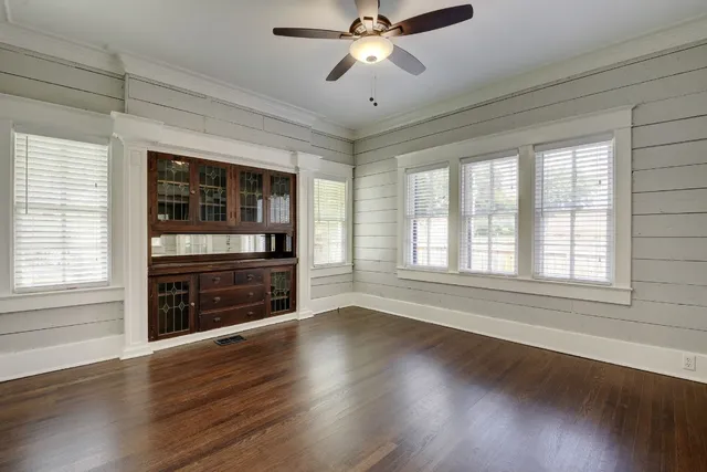 an empty room with wooden floor fan and windows