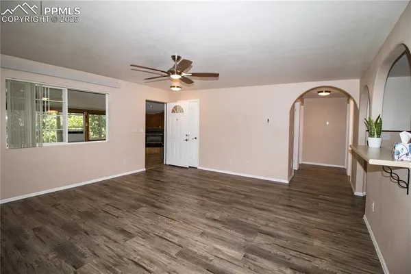 a view of an empty room with window and wooden floor