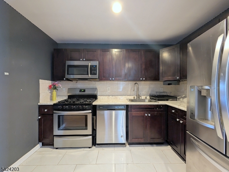 448 Fulton Street Elizabeth Port, NJ 07206 - Photo 20 of 37 a kitchen with stainless steel appliances granite countertop a stove top oven a sink and dishwasher a refrigerator with wooden cabinets