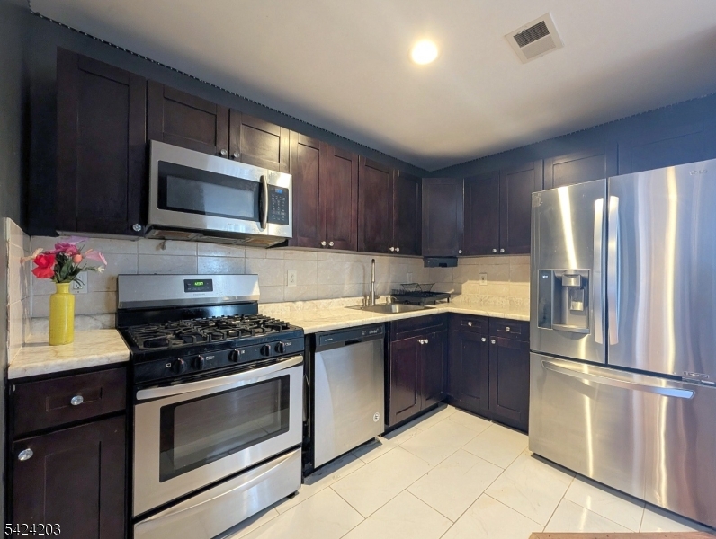 448 Fulton Street Elizabeth Port, NJ 07206 - Photo 21 of 37 a kitchen with granite countertop wooden cabinets a stove top oven and stainless steel appliances