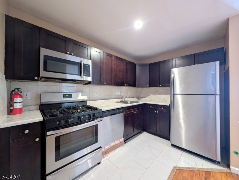 448 Fulton Street Elizabeth Port, NJ 07206 - Photo 7 of 37 a kitchen with granite countertop wooden cabinets stainless steel appliances and a counter space