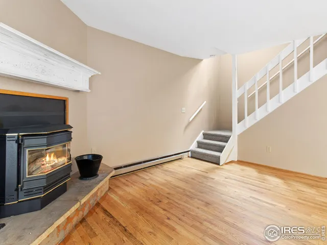 a view of an empty room with wooden floor and a fireplace