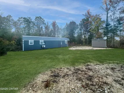 a view of a house with a yard and a large tree