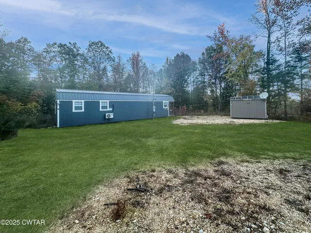 a view of a house with a yard and a large tree
