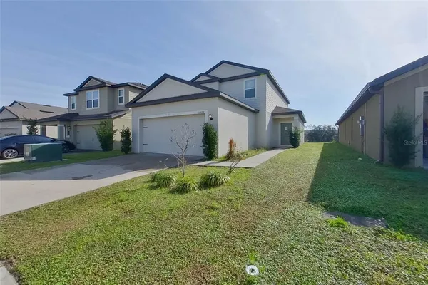 a view of a house with a big yard and large tree
