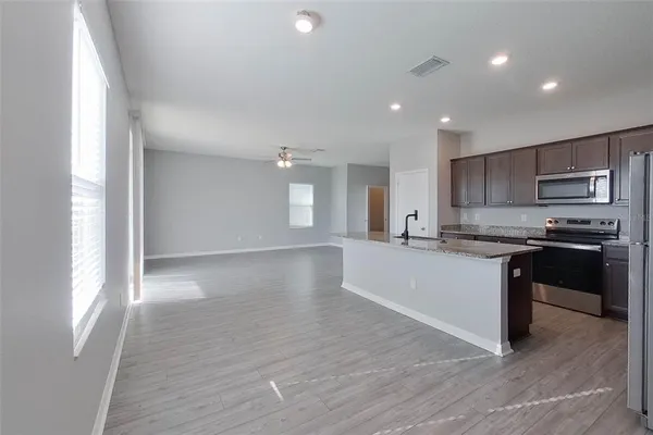 a large kitchen with kitchen island granite countertop a large counter top space a sink stainless steel appliances and cabinets