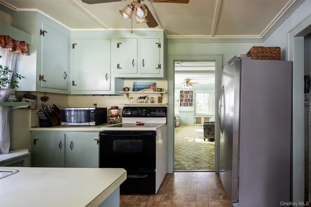 a kitchen with kitchen island granite countertop a refrigerator a sink a stove and white cabinets